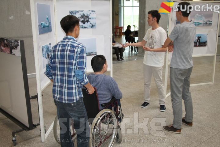 Талгат келген көрүүчүлөргө ар бир сүрөтүн тааныштырып жатты.